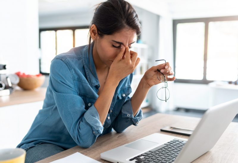 Shot of stressed business woman working from home on laptop looking worried, tired and overwhelmed.