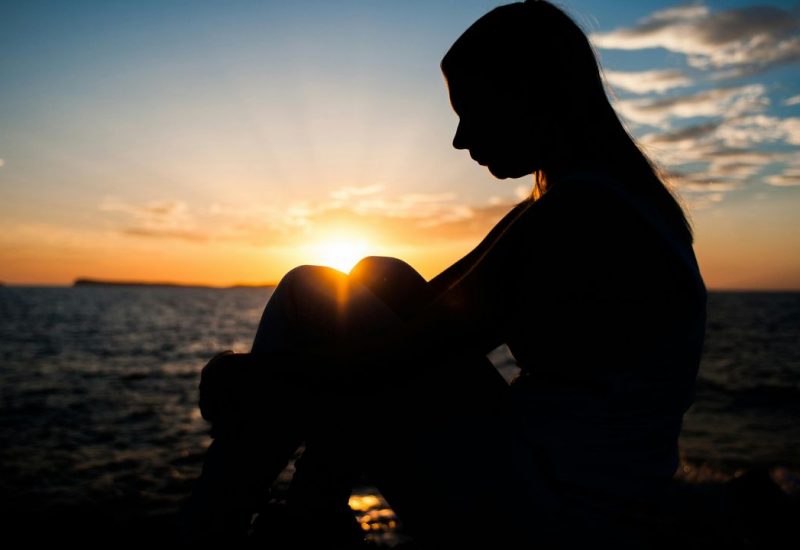 Photo of a woman sitting in the sunset. For grief counseling contact Mason today.